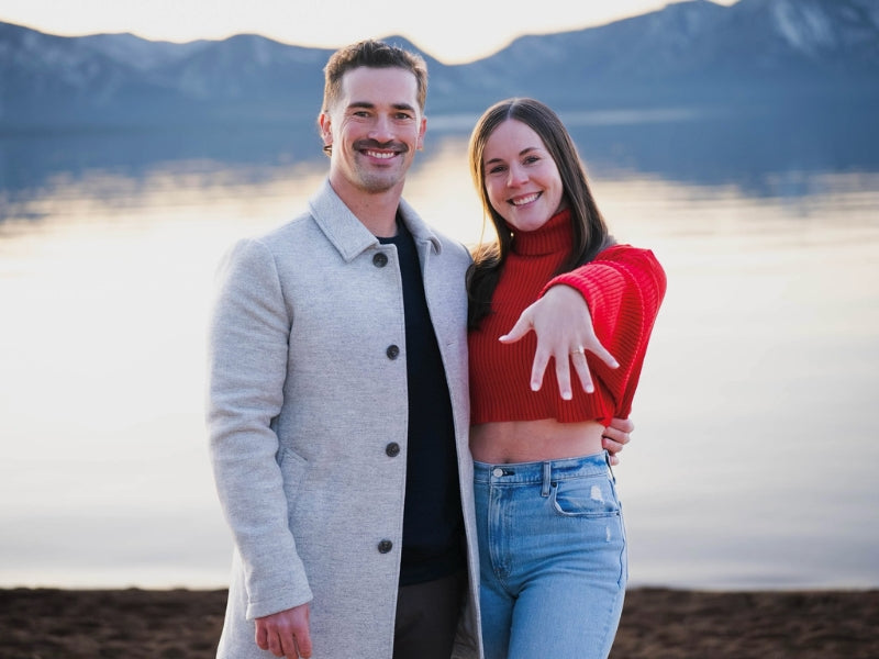 Newly engaged couple showing custom Sakaris Jewelers engagement ring at the lake