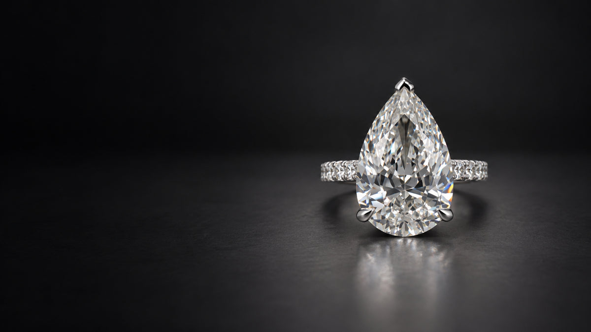 Custom pear-shaped diamond engagement ring with a pavé diamond band, designed by Sakaris Jewelers in Naples, Florida