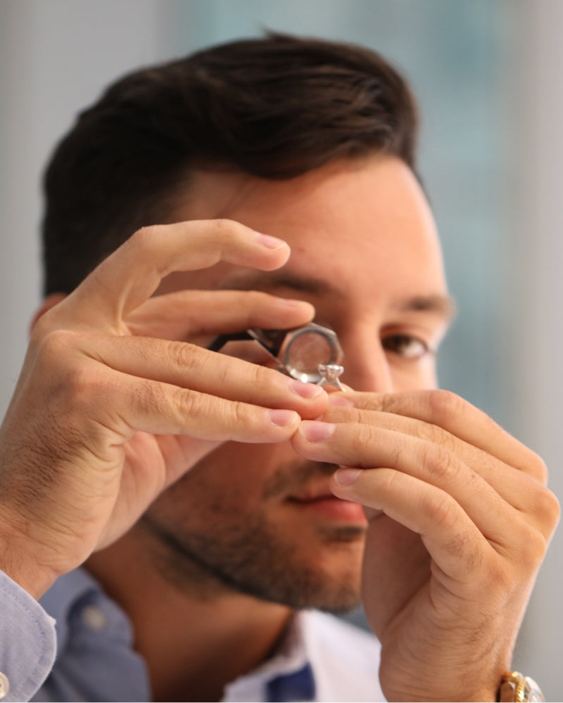 Peter Sakaris examining a diamond with a loupe at Sakaris Jewelers private design studio Naples Florida