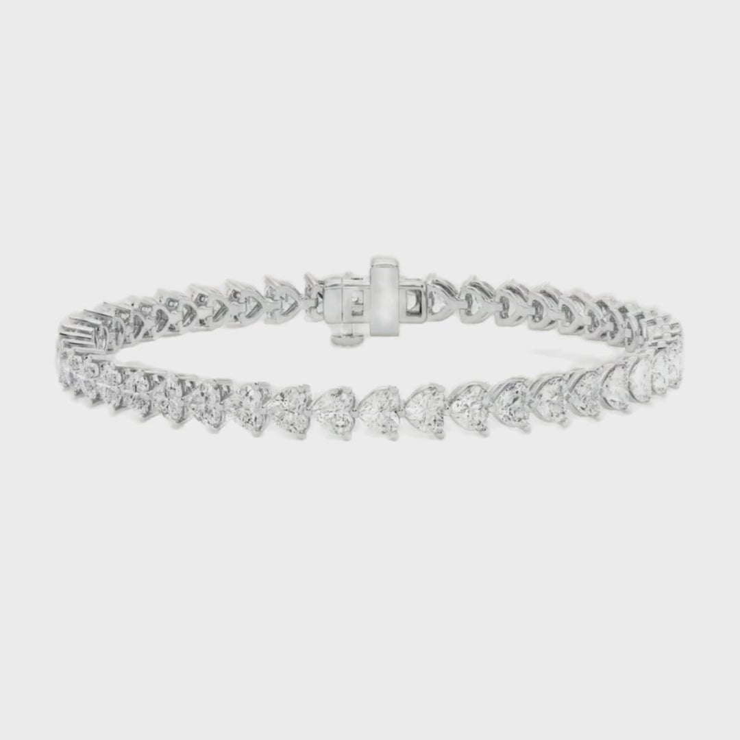 A gold tennis bracelet featuring a continuous row of heart-shaped diamonds, designed for elegance and romantic sophistication.