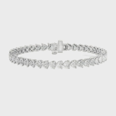 A gold tennis bracelet featuring a continuous row of heart-shaped diamonds, designed for elegance and romantic sophistication.