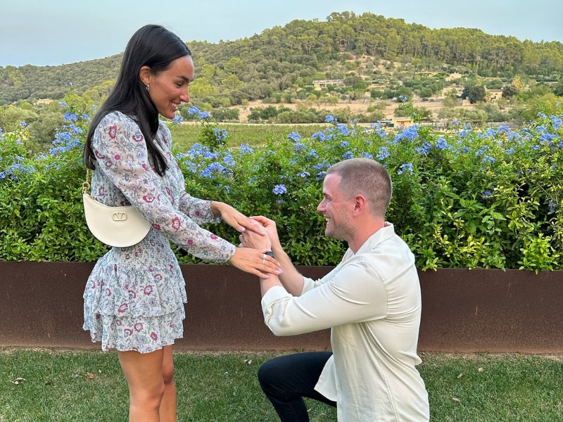 Man proposing with custom Sakaris Jewelers engagement ring on European terrace