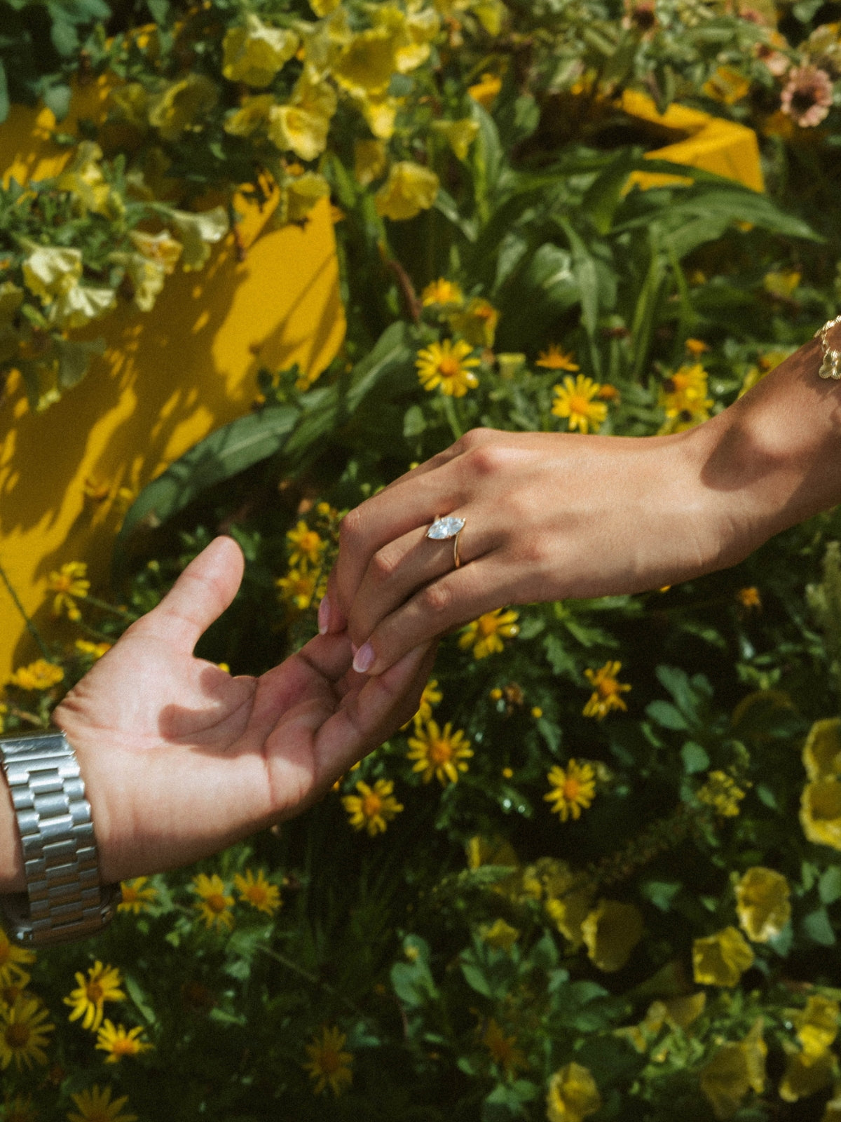 Couple reaching for each other after a marriage proposal wearing a custom engagement ring designed by Sakaris Jewelers Naples Florida